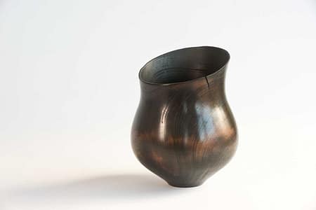 Hollowed wooden vessel with natural grain showing beneath fire-blackened finish.