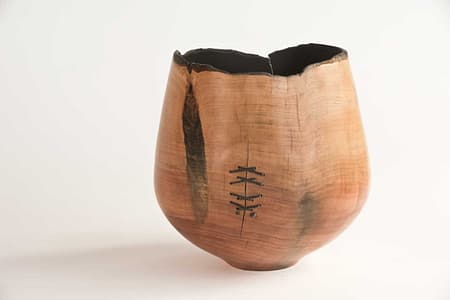 Totara bowl with bark edge and waxed cord stitching, featuring a fire-darkened interior