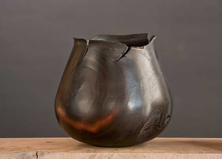 Cracked and sculpted vessel with dramatic flame-shaped rim and rich black surface.